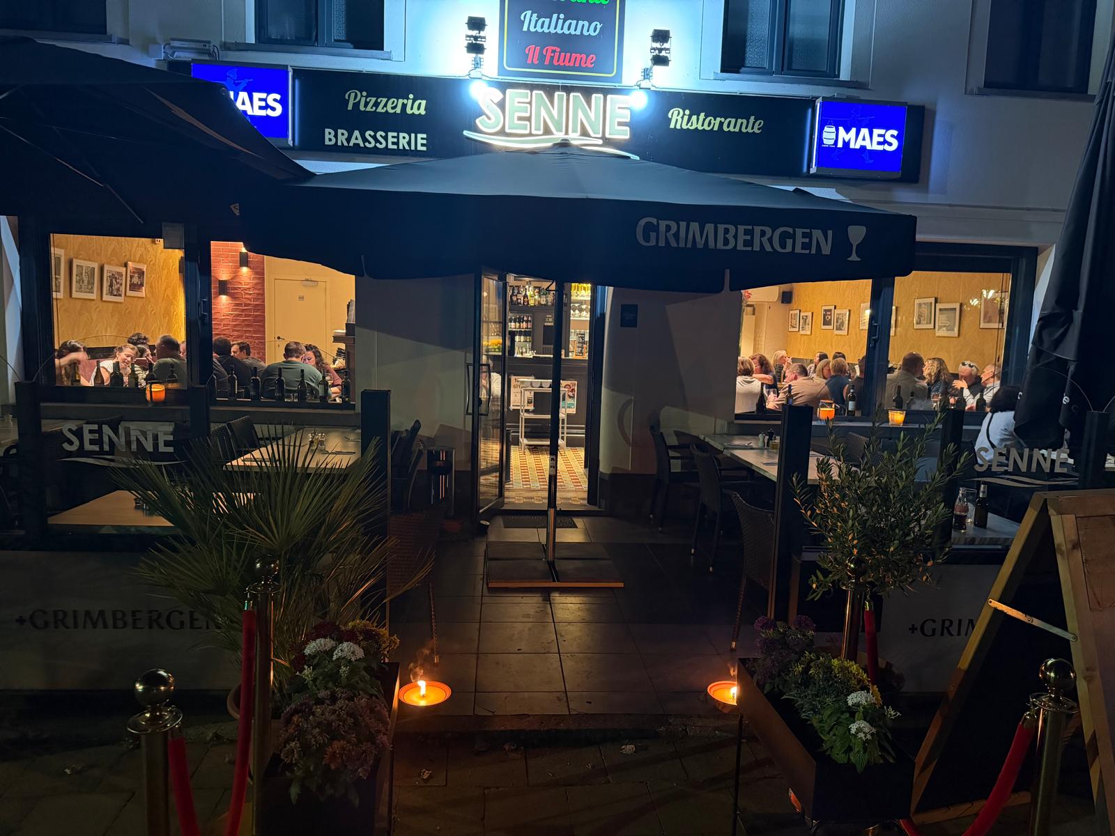 Terrasse et devanture illuminée d’Il Fiume Senne le soir